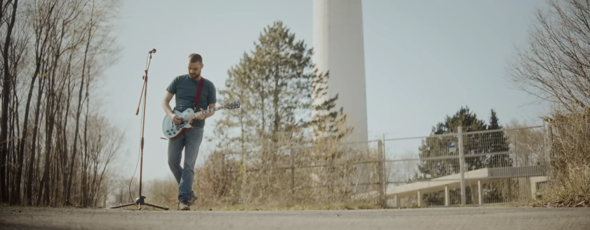 Dusan playing guitar on an empty road next to a microphone stand