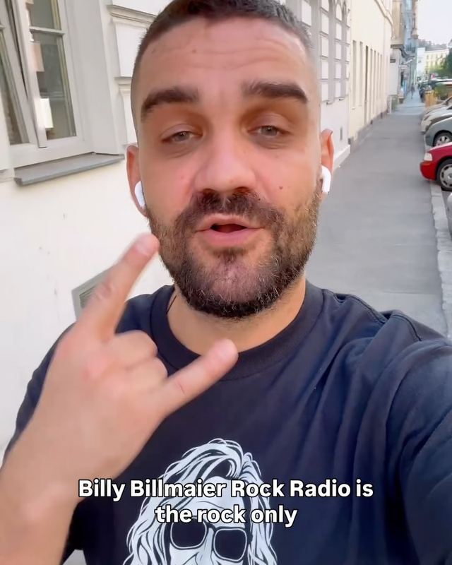 Dusan on a Vienna street in a rock radio t-shirt, making the horns sign