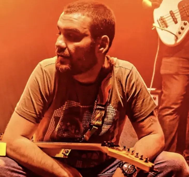 Dusan with an electric guitar under warm stage light